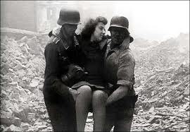 German soldiers help a Berlin woman escape from a collapsed cellar after a bombing raid.
